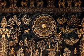 Wat Xieng Thong temple in Luang Prabang, Laos. Detail of the  intricate gold stencilling on black lacquer that decorate the walls of the sim. 